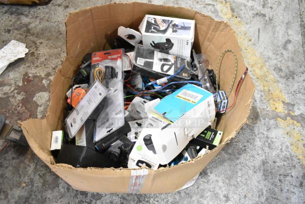 Tier lot of assorted items in a large box, including car chargers, various chargers, and Zebra label rolls. Mixed condition.
