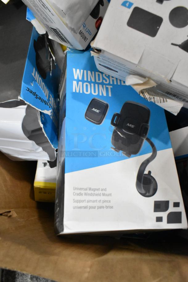 Lot of various items, primarily phone mounts, in original packaging. Includes MS windshield mount with universal magnet. Some boxes show minor wear.