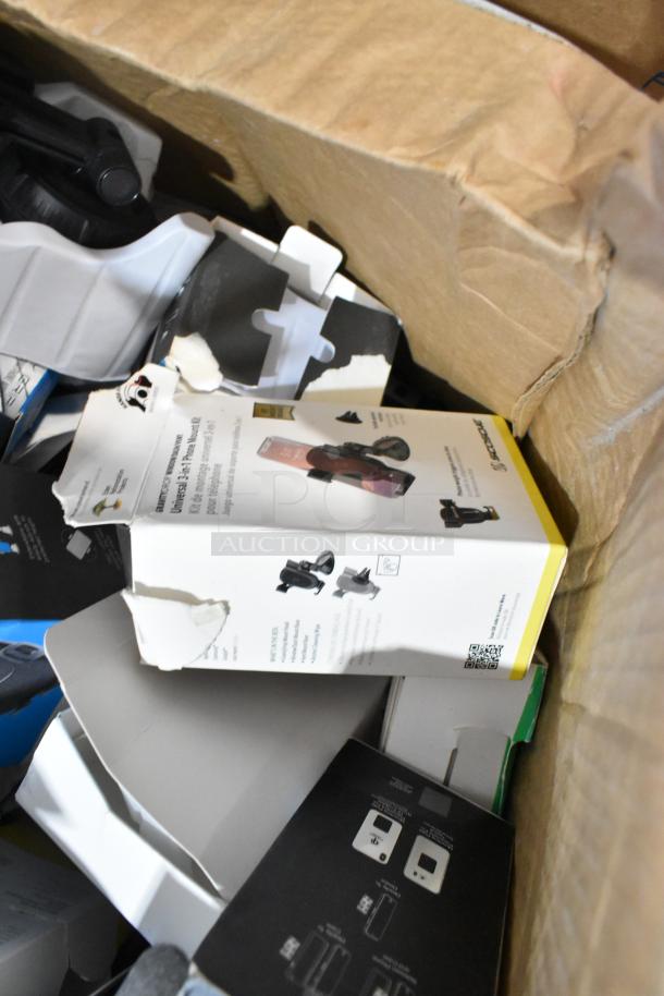 Lot of various items in a box, includes multiple phone mounts. Visible packaging shows slight wear, indicating pre-owned condition.