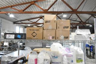 Tier lot featuring Pendaflex SureHook hanging box files, Purell white soap dispenser boxes, and receipt printer rolls. Items on a metal shelf.