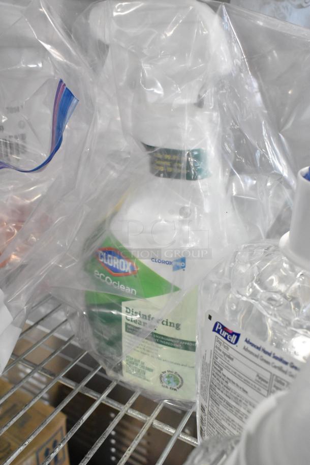 Assorted item lot with Clorox disinfectant and Purell sanitizer bottles, sealed in clear plastic bags, on a wire shelf.