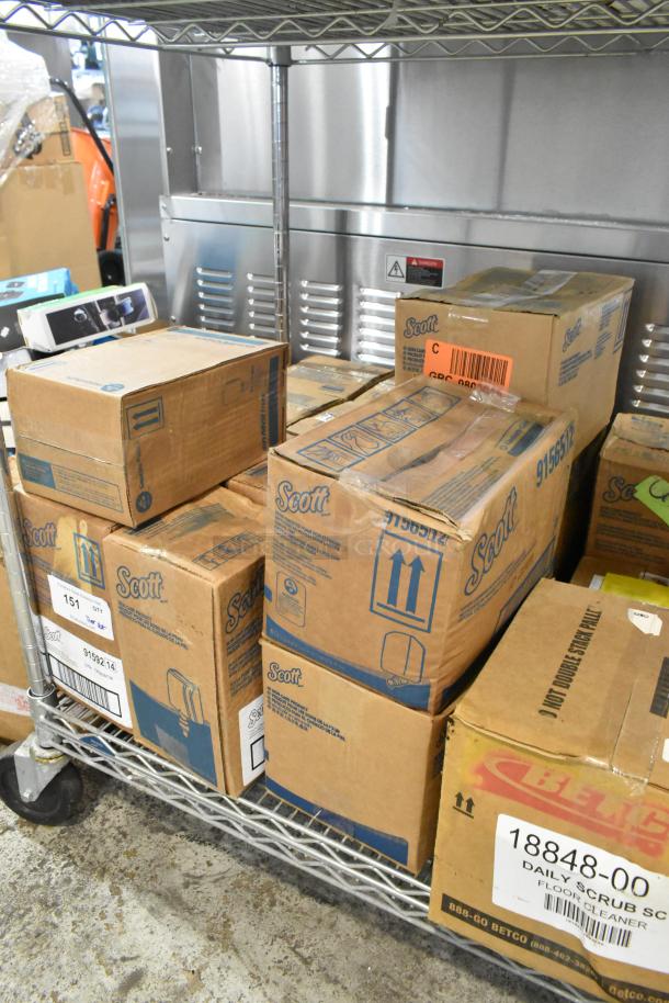Boxes on a metal shelf including Scott dispensers and Betco daily scrub, indicating multiple cleaning items in bulk.