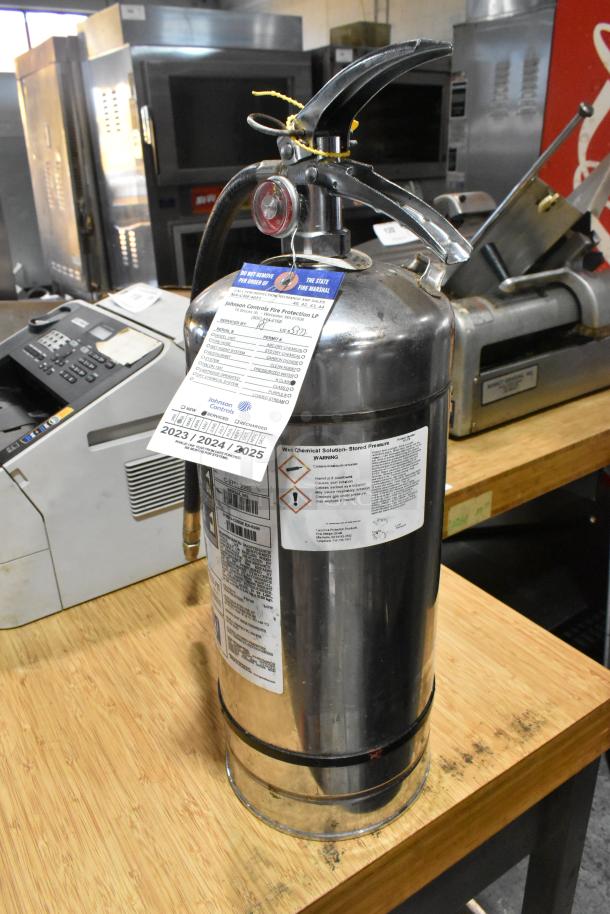 Brand new Kitchen One wet chemical fire extinguisher, stainless steel, featuring safety tags and usage instructions, sold as scratch and dent.