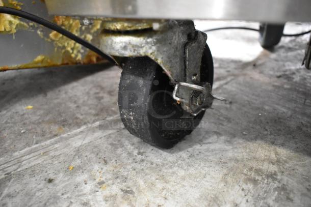 Silver King chest freezer caster, showing wear and grime on stainless steel base and wheel mechanism, indicating used condition.