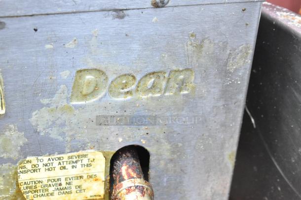 Dean stainless steel commercial fryer oil filtration system with visible wear. Engraved "Dean" logo and caution label.