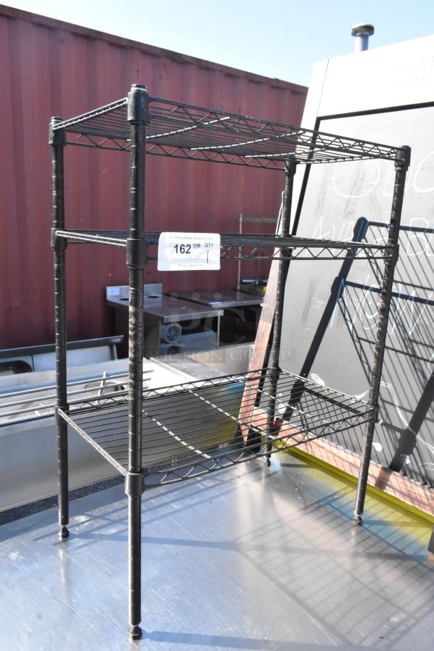Black finish 3-tier wire shelving unit, sturdy construction, dismantling required by buyer, visible label with auction info.