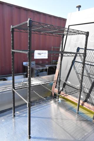 Black finish 3-tier wire shelving unit, sturdy construction, dismantling required by buyer, visible label with auction info.