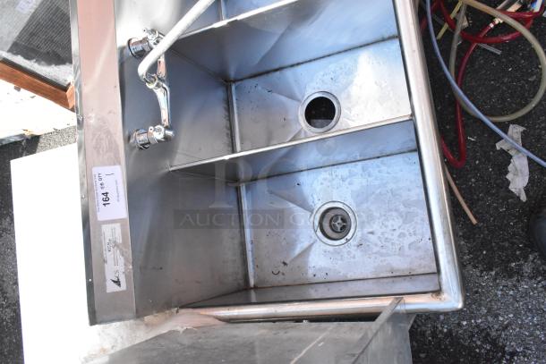 Stainless steel 3 bay sink with attached faucet and handles, visible wear, and auction tag numbered 164.