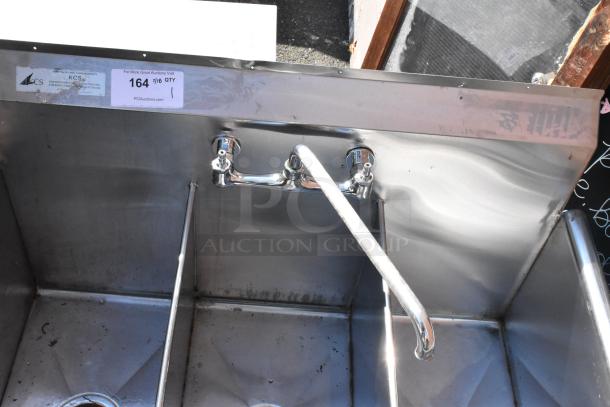 Stainless steel 3 bay sink with faucet and handles, used condition, industrial-grade, measuring sticker "164" visible.
