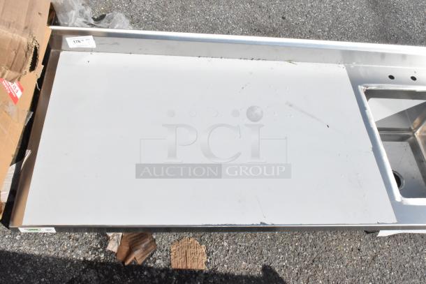Brand new Regency 600ST3072R stainless steel table with sink bay, no legs, visible minor scratches and dents.