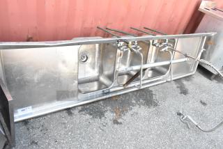 Stainless steel 3 bay sink with dual drain boards, faucet, and handles; appears in used condition.