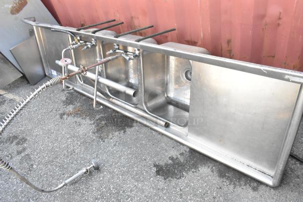 Stainless steel 3-bay sink with dual drain boards, faucet, and handles. Good condition. Ideal for commercial kitchens.