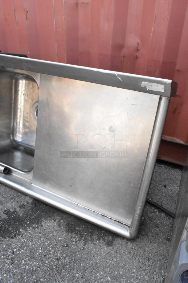 Stainless steel 3 bay sink with dual drain boards, faucet handling, and slight wear. Ideal for commercial use.