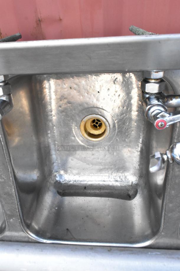 Stainless steel 3 bay sink with dual drain boards, faucet, and handles; features visible wear.