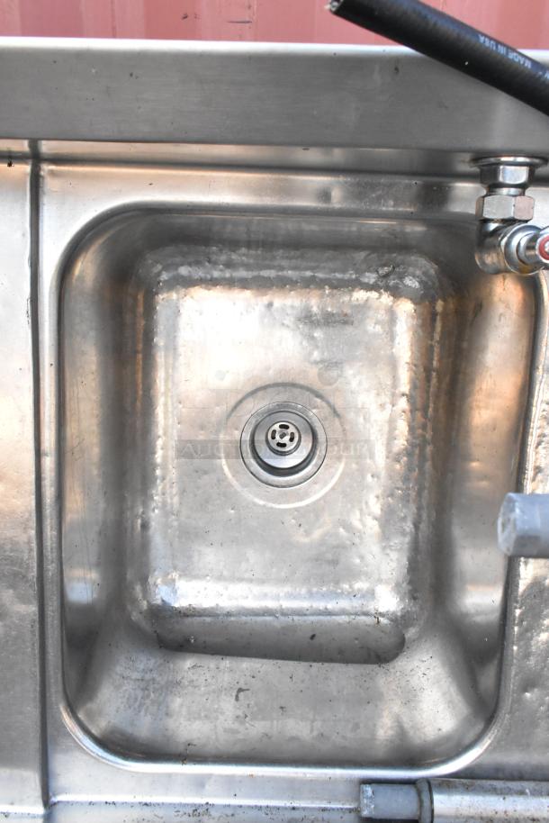 Stainless steel 3 bay sink with dual drain boards, faucet, and handles, showcasing durable construction and utility features.