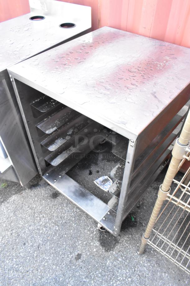 Stainless steel pan transport rack on commercial casters, used condition, multiple shelves, suitable for kitchen use.