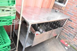 Stainless steel table with under shelf and two pan racks, showing wear; ideal for commercial kitchen use.
