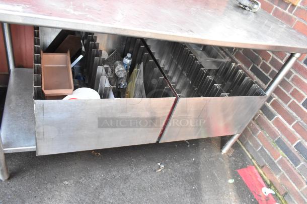 Stainless steel table with under shelf, holds 2 pan racks, some wear visible, suitable for kitchen use.