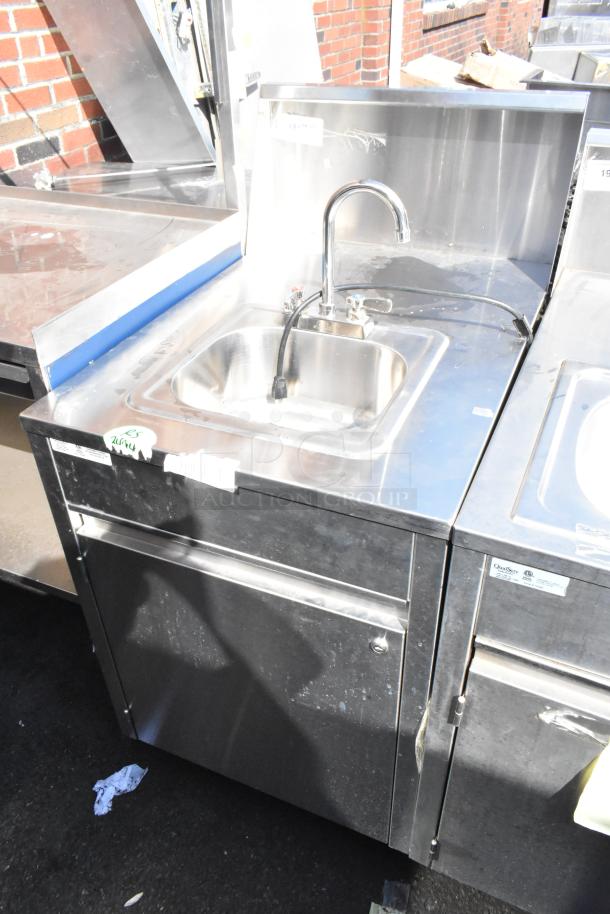 QualServ stainless steel commercial portable sink with faucet on commercial casters, visibly used, with manufacturer's label.