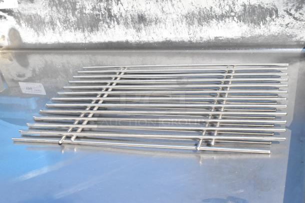 Stainless steel table with cut-out top and under shelf, shows minimal wear. Metal grate present on surface.