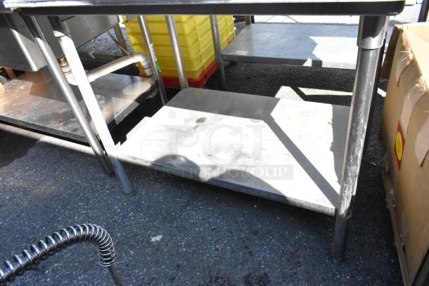Stainless steel table with cut out and under shelf, used condition, sturdy design, visible pipe connections.