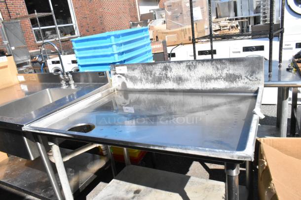 Stainless steel table with a cut-out and under shelf, features a backsplash and faucet. Good condition, ideal for commercial use.