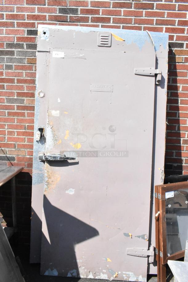 Storflex walk-in box door with frame, industrial design, visible wear and paint peeling, embossed Storflex logo.