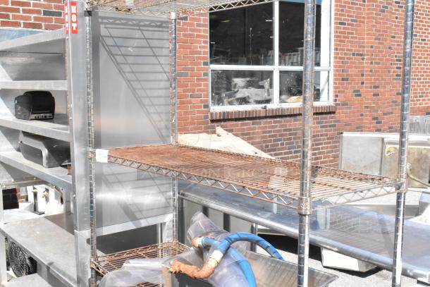 Chrome finish 4-tier wire shelving unit outdoors. Buyer must dismantle. Consider freight charges.