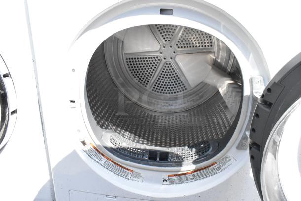 Whirlpool front load dryer with metal drum, open door view, visible safety labels, standard size.