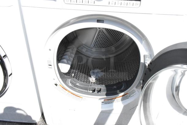 Whirlpool front load dryer with metal exterior, open door showing drum, control panel visible. Good condition.