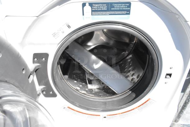 Whirlpool WFW5620HW2 front load washer, metal finish, open door view; model and voltage label visible inside.