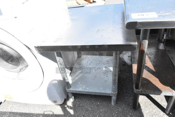 Stainless steel table with metal under shelf, used condition, visible surface marks, sturdy legs, tag number 231 attached.