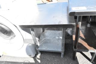 Stainless steel table with metal under shelf, used condition, visible surface marks, sturdy legs, tag number 231 attached.