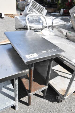 Stainless steel table with metal under shelf, visible wear, label marked "232", suitable for industrial use.