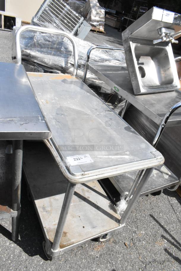 Metal 2-tier cart with commercial casters, sturdy construction. Some surface wear. Label reads "233." Ideal for transport.