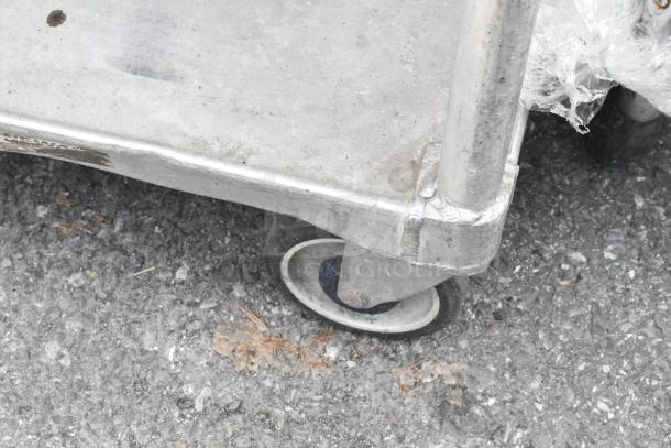Metal 2-tier cart with commercial casters, showing signs of wear. Features sturdy construction and smooth mobility.