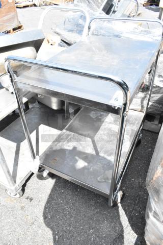 Stainless steel 2-tier cart on commercial casters, durable construction, ideal for transport and storage, shows light wear.