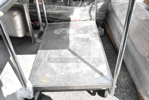 Stainless steel 2-tier cart on commercial casters, featuring sturdy shelves and a polished finish. Ideal for industrial use.