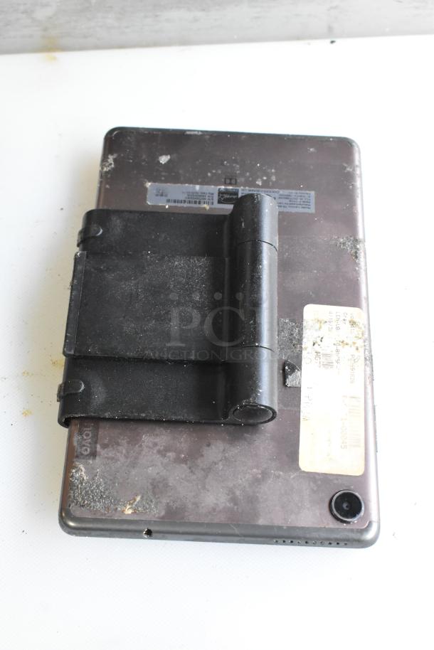 Five tablets including Lenovo TB-8505F, visible wear, attached black stand, labels with serial numbers.