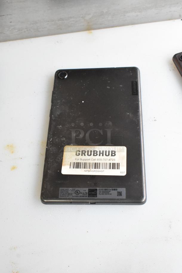 Five tablets, including a Lenovo TB-8505F, with visible wear. Grubhub label shows support contact and code NPNHGR2GHGT.