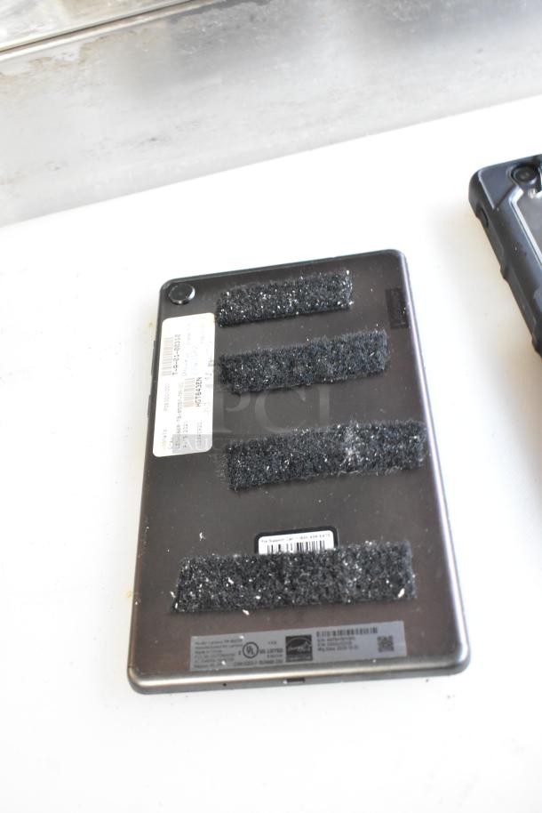 Five tablets, including Lenovo TB-8505F, backside view with adhesive strips, factory labels, and model details visible.