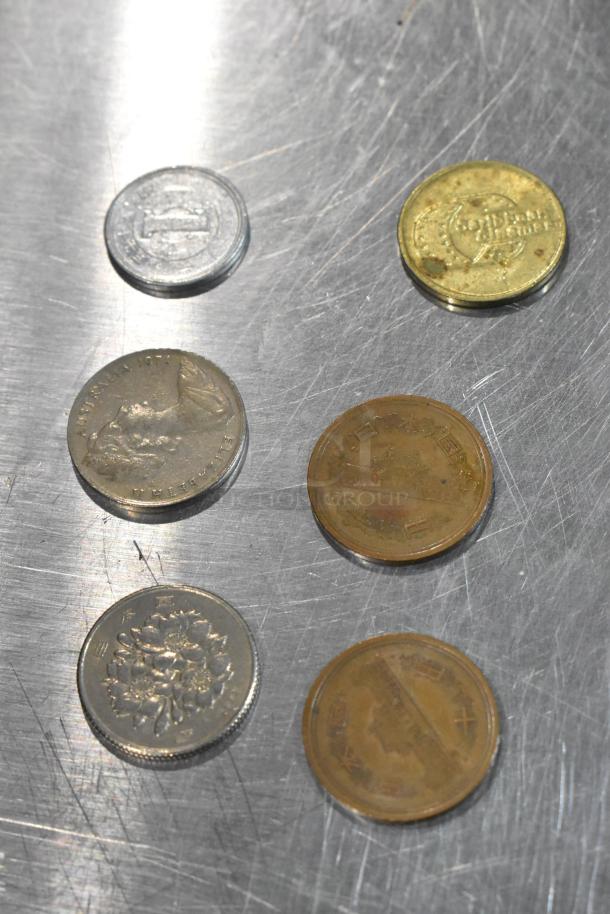 Lot of 24 various coins on metallic surface; includes different currencies, visible markings, mixed conditions.