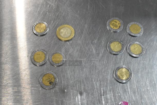 Lot of 10 various coins on silver surface; coins feature different designs and appear in varying conditions.