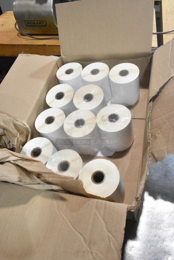 Box of 12 brand new thermal receipt printer rolls, wrapped in plastic, in an open cardboard box. Rolls are white, unused, and ready for printing.