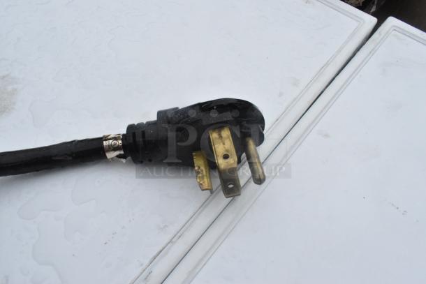 Close-up of a power plug for a Whirlpool metal front load dryer, suitable for 125/250 volts. Plug shows signs of wear.