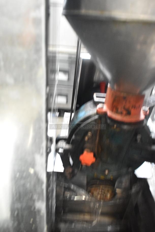 Blurry image of a metal commercial floor-style unit showing part of a hopper and mechanical components. Condition unclear.