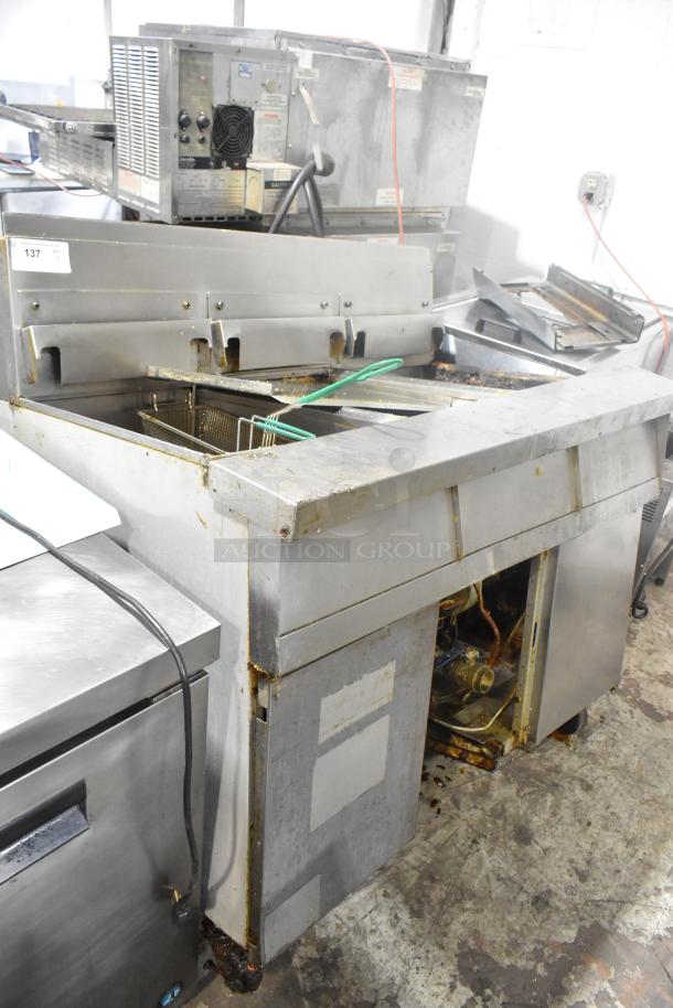 Stainless steel commercial natural gas 3-bay deep fat fryer, used condition, visible surface wear, includes frying baskets.