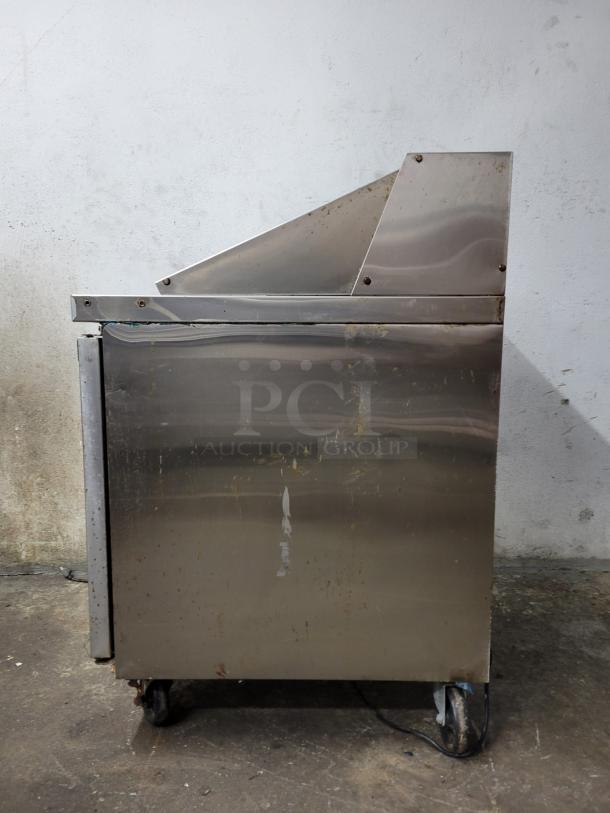 Dukers Salad Prep Station Refrigerator DSWP29, stainless steel, model DSP29, visible wear, on wheels, plugged in.