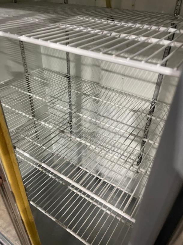 Leader commercial stainless steel merchandiser refrigerator with double glass sliding doors and poly coated wire racks.
