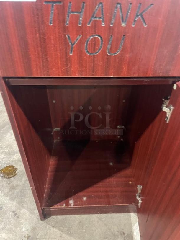Commercial wooden waste receptacle with "Thank You" engraving, open door, showcasing interior space. Some wear visible.